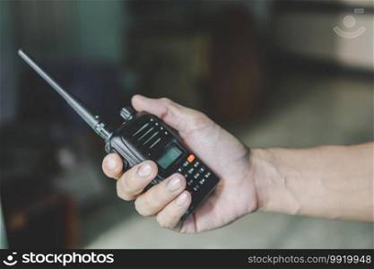 The hand of a man holding a walkie-talkie radio