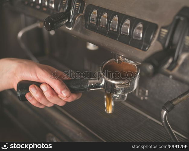 The hand of a young woman is operating a professional coffee machine