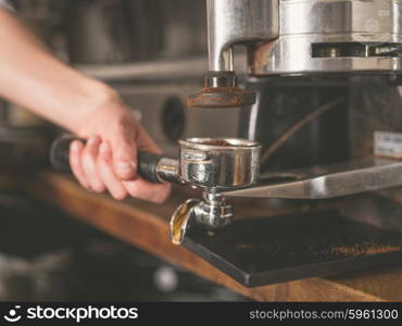 The hand of a young woman is operating a professional coffee machine
