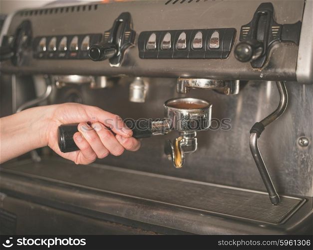 The hand of a young woman is operating a professional coffee machine