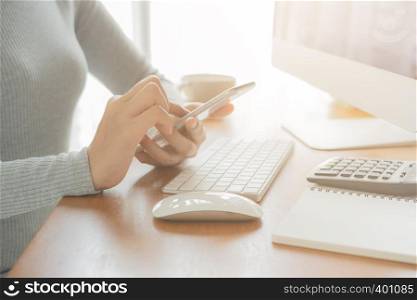 The hand of Asian women are using smartphone and computer in the office. Young women are using phones in social networks.