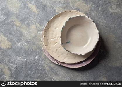The handmade porcelain dishes, bowls on a gray marble table with space under text. Top view.. Traditional decorative handcrafted clay dishes, covered with glazed on a gray background.