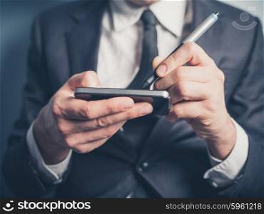 The hands of a businessman as he is using an electronic pen on his smartphone