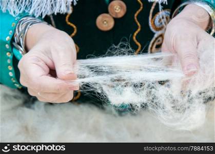 The hands of a Muslim woman working with wool
