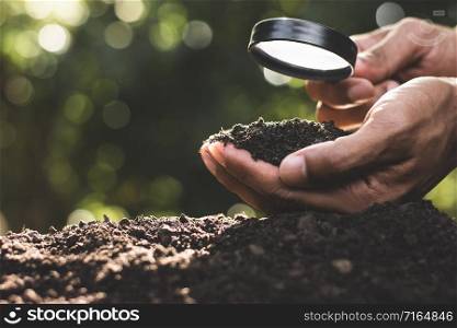 The hands of the agricultural men are picking the best soil for planting.
