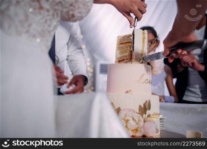 The hands of the newlyweds cut the cake into pieces.. The process of cutting the cake into pieces 3820.