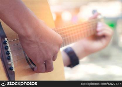 The hands playing acoustic guitar, close up