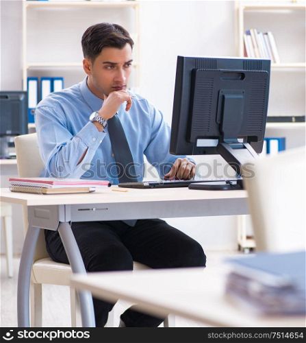 The handsome businessman employee sitting at his desk in office. Handsome businessman employee sitting at his desk in office