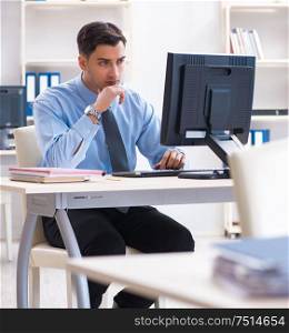 The handsome businessman employee sitting at his desk in office. Handsome businessman employee sitting at his desk in office