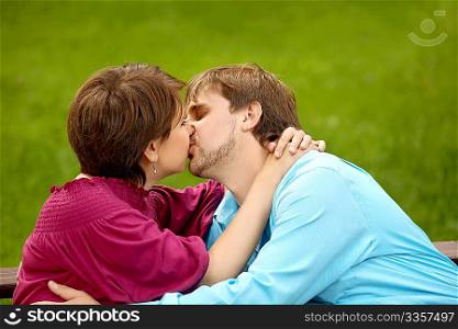 The happy adult couple kisses in park