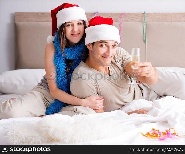 The happy couple celebrating christmas holiday in bed. Happy couple celebrating christmas holiday in bed