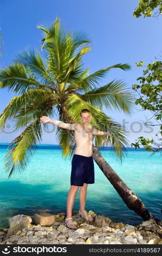 The happy teenager about a palm tree against ocean