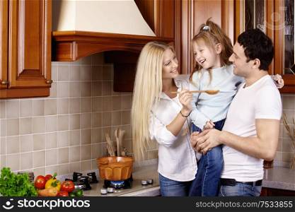 The happy young family prepares in kitchen