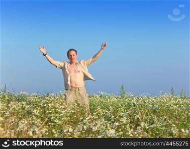 The happy young man in the field of chamomiles