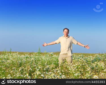 The happy young man in the field of chamomiles