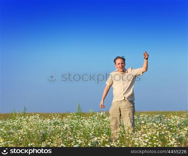 The happy young man jumps in the field of chamomiles
