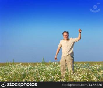 The happy young man jumps in the field of chamomiles