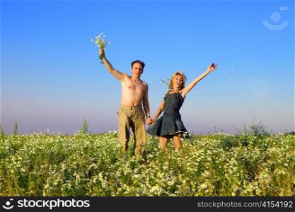 The happy young pair in the field of chamomiles