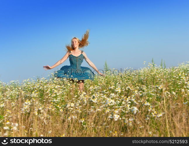 The happy young woman in the field of camomiles