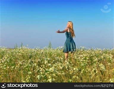 The happy young woman in the field of camomiles