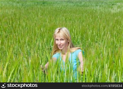 The happy young woman in the field of green ears