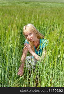 The happy young woman in the field of green ears