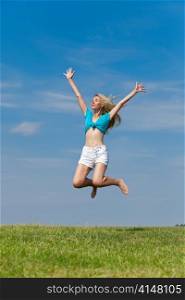 The happy young woman jumps in the field