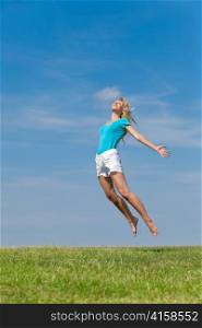 The happy young woman jumps in the field