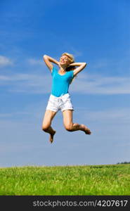 The happy young woman jumps in the field