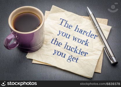 The harder you work, the luckier you get - inspirational handwriting on a napkin with cup of coffee against gray slate stone background