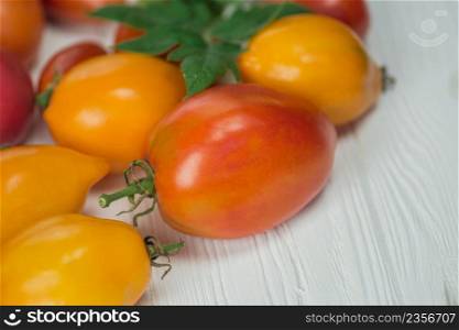 The harvest of assorted tomatoes. Variety ripe natural organic delicious different tomatoes. Tomatoes on wooden background.. Different colorful tomatoes on wooden background. Organic green, red, yellow, orange tomatoes.