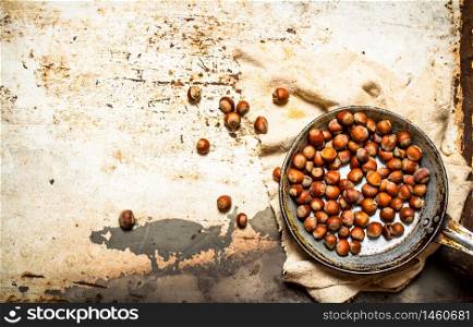 The hazelnuts in an old pan. On rustic background.. The hazelnuts in an old pan.