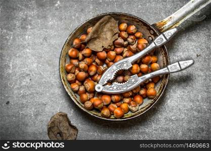 The hazelnuts in an old pan. On the stone table.. The hazelnuts in an old pan.