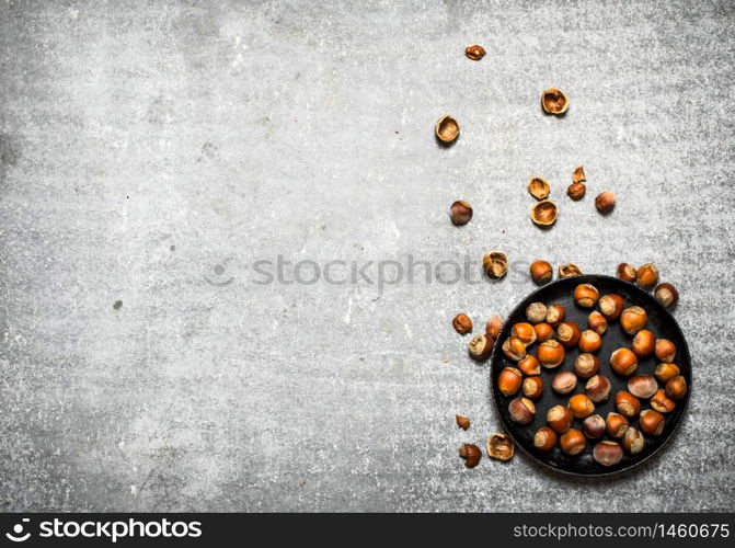 The hazelnuts in an old pan. On the stone table.. The hazelnuts in an old pan.