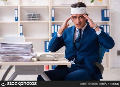 The head injured male employee working in the office. Head injured male employee working in the office