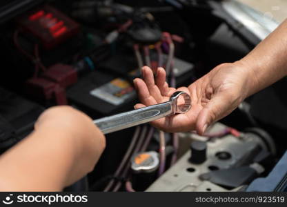 The head of technician the car engine repairman service is sending a wrench to the co-worker. Concept of maintenance vehicle mechanic and automotive