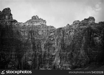 The headwall of the cirque that looms over Iceberg Lake. The cliffs on the mountains form a perfect ampitheater around the lake. Shadows from clouds provide contrast. In black and white.