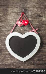 The heart shape chalkboard over old wooden background. The heart shape chalkboard