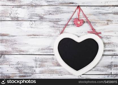 The heart shape chalkboard over shabby wooden background