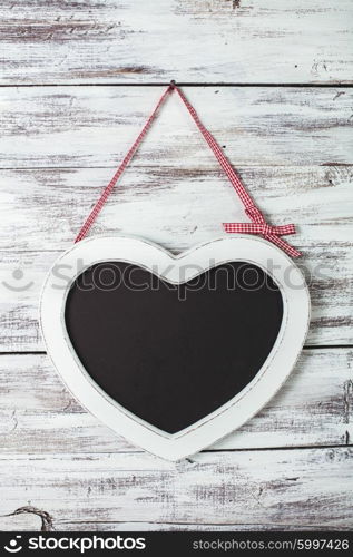 The heart shape chalkboard over shabby wooden background. The heart shape chalkboard