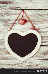 The heart shape chalkboard over shabby wooden background. The heart shape chalkboard