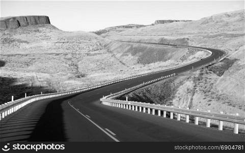 The highway winds around hills here in monochrome