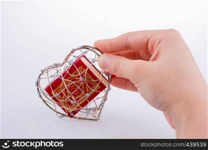 The Holy Quran in a heart shaped cage on a white background
