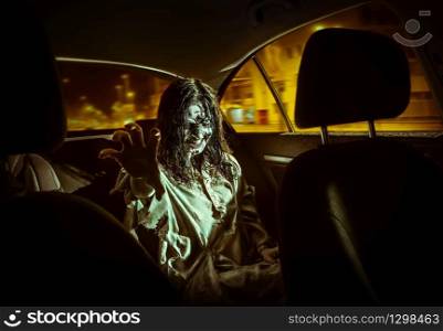 The horror zombie woman with bloody face in the car, night city on the background.. Horror zombie woman with bloody face in the car