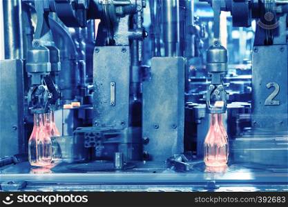 The hot glass bottles on conveyor are made by the glass manufacturer. Hot red bottles move along the conveyor at the factory. Toning. The hot glass bottles on conveyor are made by the glass manufact