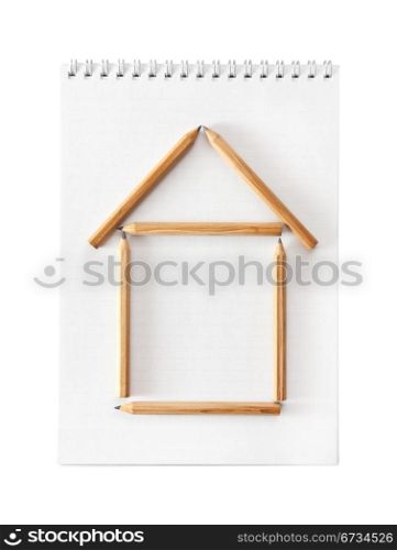 The house combined from pencils isolated on a white, notebook on background