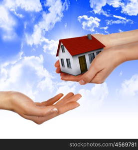 The House in the hands against the blue sky as a symbol of the real estate business.