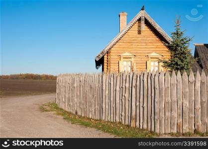The house in village. The wooden house with a fence