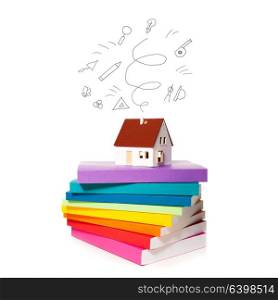 The house miniature on a stack of colorful books isolated on white background. Concept of development of a plan for construction. Development of a plan for construction