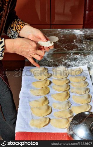 The housewife cooked raw dumplings and laid them on a cloth for subsequent cooking. Ukrainian national cuisine, close-up.. Woman spreads the finished raw dumplings on a tissue napkin.
